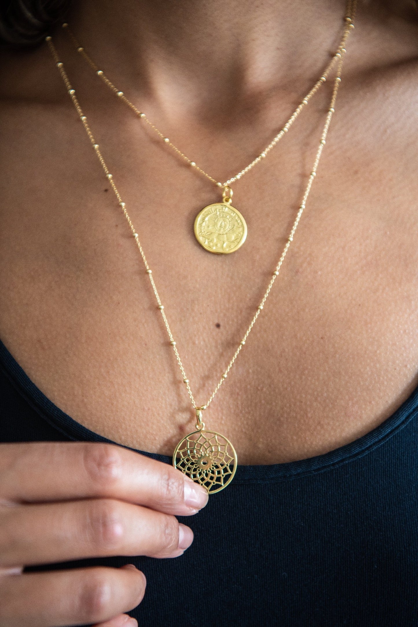 Woman wearing Lotus Mandala Necklace and holding it