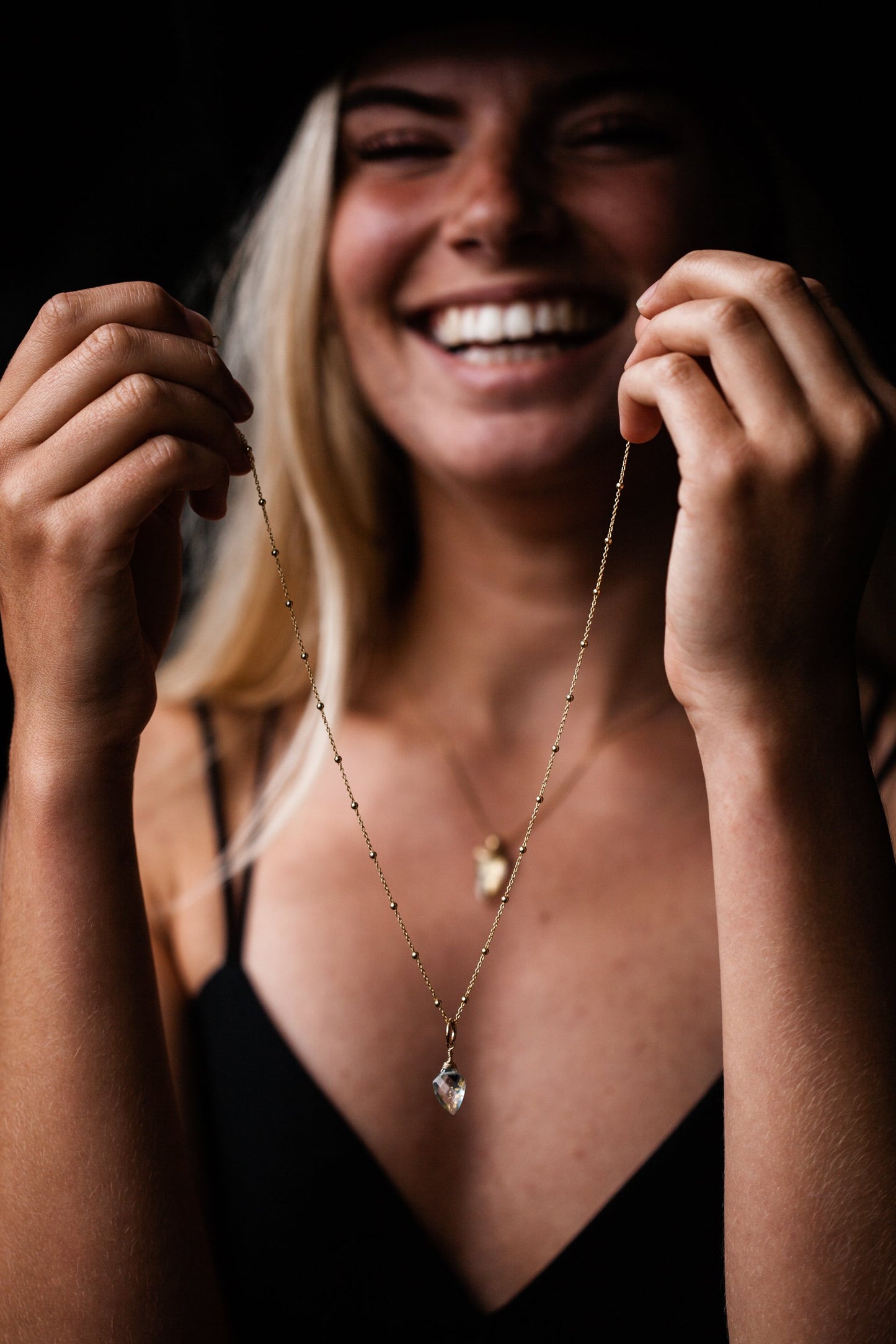 Woman holding unfastened Guardian Blue Topaz Shield Satellite Chain Necklace