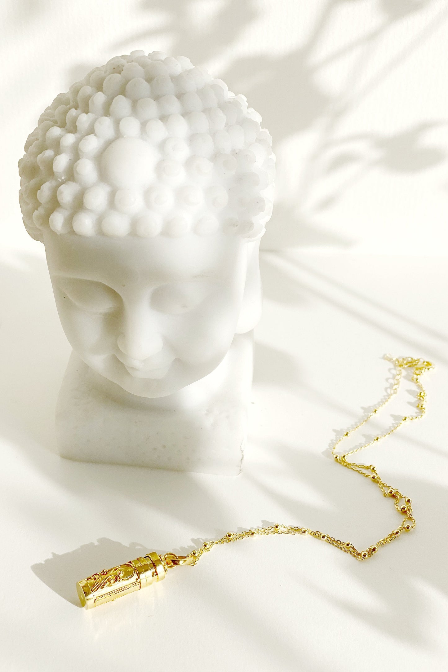 Antiena Wishing Locket on a surface beside a bust