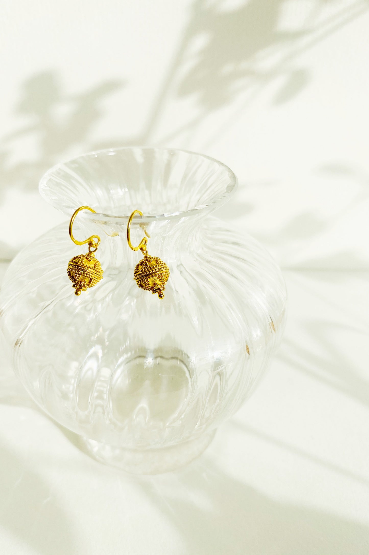Triangle Dot Harmony Ball Earrings hanging over rim of glass vase