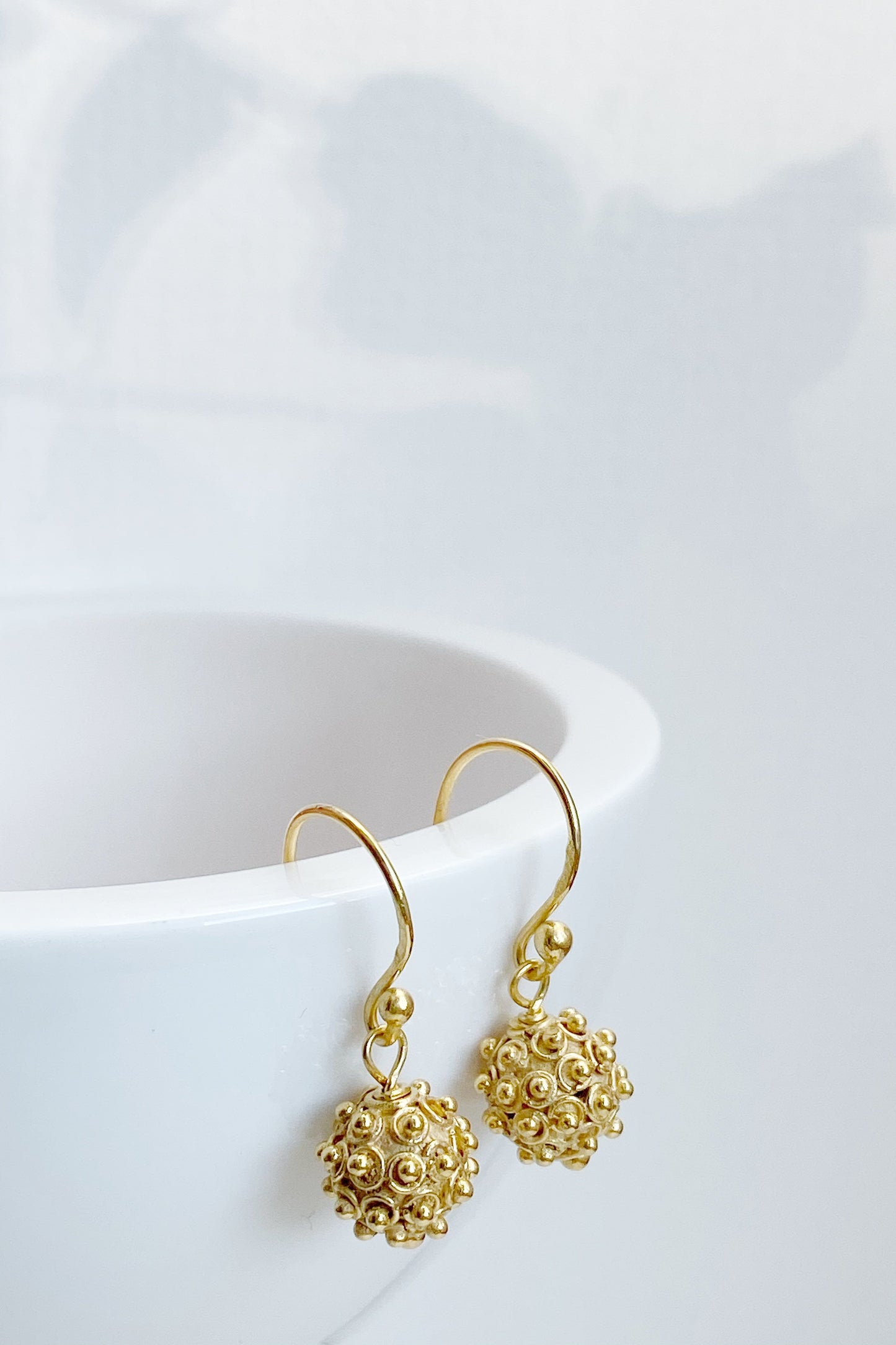 Bobble Design Harmony Ball Earrings hanging over a rim